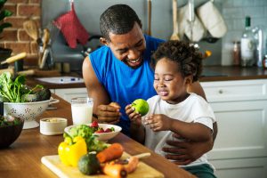 Imagem pai e filho juntos na cozinha manuseando alimentos naturais